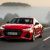 A red Audi A7 Sportback speeds along a rural road.