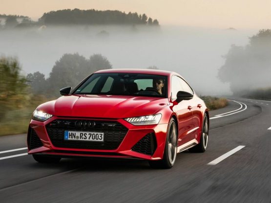 A red Audi A7 Sportback speeds along a rural road.